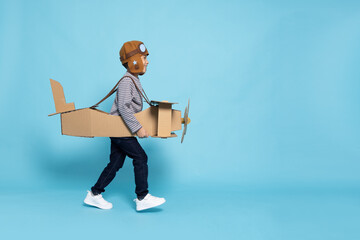 Asian little boy aviator running and playing with cardboard airplane isolated on blue sky background, Kid toy diy concept - 667781147