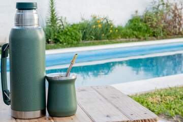 Fototapeta na wymiar Thermos and mate, next to the pool on a table