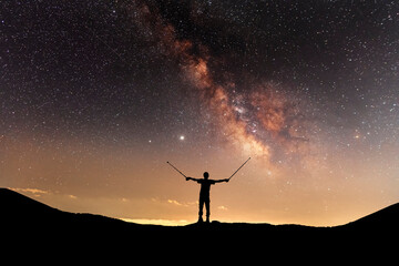 Fototapeta premium Silhouette of a hiker standing on the hill, on the milky way galaxy background.