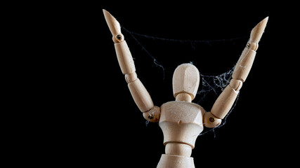 A wooden mannequin with raised arms is covered with cobwebs.