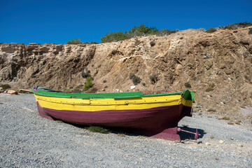 Vintage wooden fishing boat moored on empty pebble coast background. Gavdos island Crete Greece.