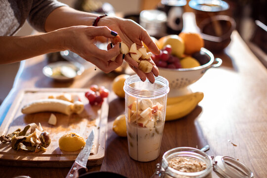 Close up of a young woman putting sliced bananas in a blender