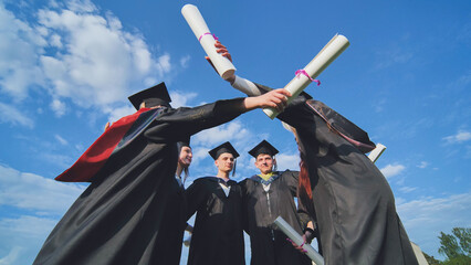 College graduates embrace in a circle.