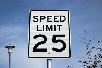 A white sign against a blue sky informing drivers that the speed limit is 25 miles per hour.  © Viktoriya