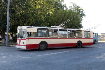 On a summer day there is a trolleybus in the parking lot.
