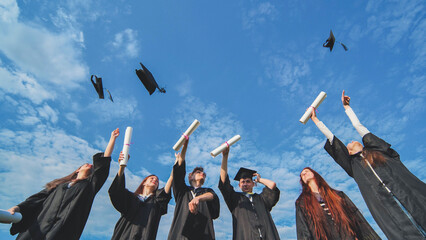 Joyful graduates stand in a row and toss their caps up in the air.
