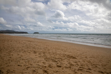 Beautiful beach on a cloudy day. Sandy beach. Waves on the sea.