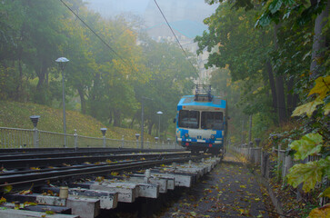 Scenic foggy autumn landscape with the Kyiv Funicular. Cabins with passengers goings to the lower station. Funicular is popular transport among locals and tourists. Travel and tourism concept