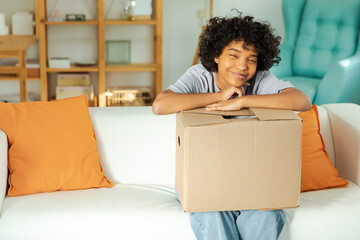 African girl unpacking delivery looking in box. Happy woman opening carton box. Female getting...