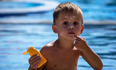 child by the pool applying sunscreen.
