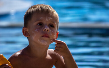 child by the pool applying sunscreen.