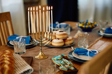 Lit menorah and table setting prepared for celebration of Jewish Festival of lights.