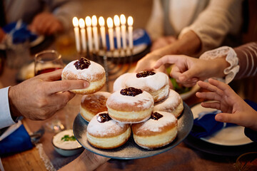 Close up of Jewish family having traditional Sufganiyah for dessert on Hanukkah. - Powered by Adobe