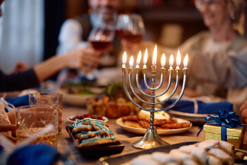 Lit candles in menorah with Jewish family toasting in background.