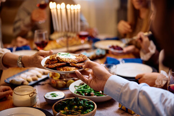 Close up of Jewish family having potato latkes during meal on Hanukkah.