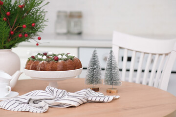 Christmas home interior in white kitchen-Christmas chocolate bundt cake with fresh berries and rosemary. Winter baking at Christmas. Ceramic vase with spruces brunches..