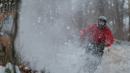 SLOW MOTION, DOF, CLOSE UP: MTB rider racing and drifting down the snowy trail. Freshly fallen snow is flying around as adrenaline seeking biker rides fast along forest path on a cold winter day.