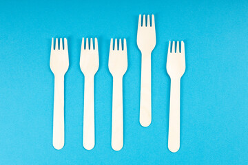 five wooden forks are laid out in a row, one of the forks is extended