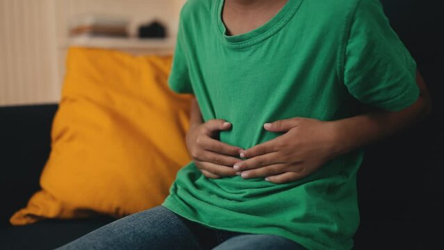Close-up of little boy holding his tummy, experiencing food poisoning symptoms. Child running to the bathroom