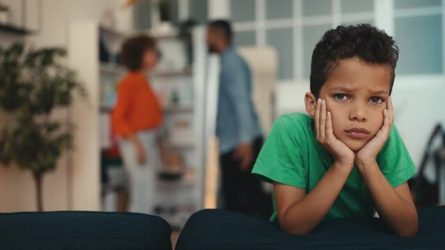 Portrait of upset African American boy with his parents fighting on background. Family having a fight, child's traumatic experience