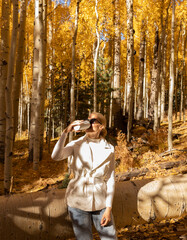 Beautiful Woman Drinks Hot Drink Coffee Or Tea From Thermos Travel Mug In Autumn Park, Forest While Hiking. Relaxed Female In Her 30s Enjoys Camping, Breathing Fresh Air In Fall Season. Vertical.