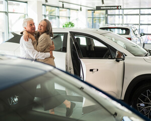 Mature Caucasian couple hugging. Elderly man and woman buying a new car. 