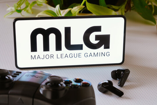 October 25, 2023, Brazil. In this photo illustration, the Major League Gaming (MLG) logo is displayed on a smartphone screen, next to a gamepad and headphones.