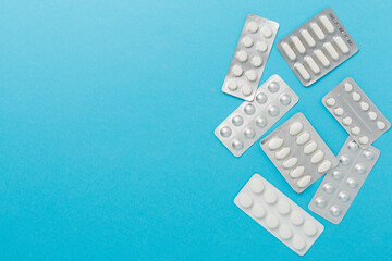 Pills in blister packaging on color background, top view