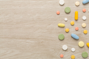 Different medical pills and capsules on wooden background, top view