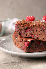 Plate with pieces of raspberry chocolate brownie on grey tile table