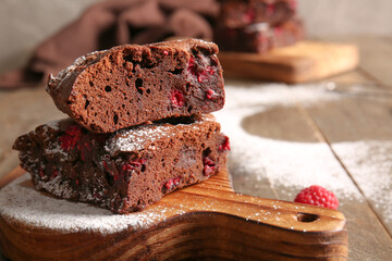 Board with pieces of raspberry chocolate brownie on wooden table