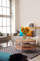 Vase with beautiful sunflowers on coffee table in interior of light living room