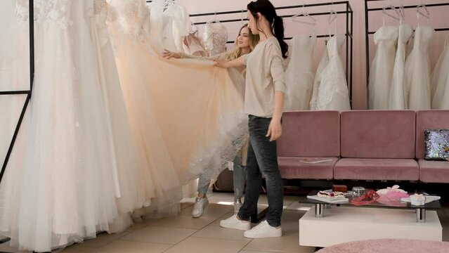 Wedding showroom with seamstress consultant. Bride to be chooses a wedding dress at the salon