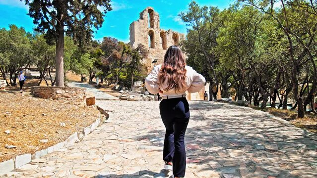 Young woman visiting the historical landmark of Acropolis in Athens, Greece. Beautiful girl exploring the ruins of the iconic temple complex on Athens' rocky hilltop.