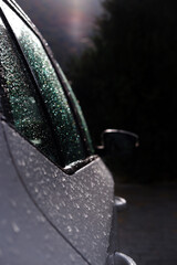 A white beautiful car in drops after the rain is standing on the street. white car. close-up, macro photography of car parts