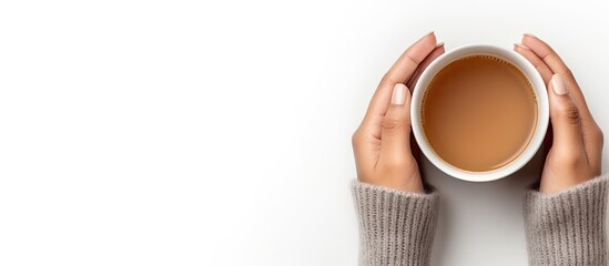 Top view photograph of woman s hands in a gray sweater holding a hot drink cup in the autumn theme on a white background