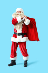 Santa Claus with bag of gifts on blue background