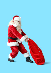 Santa Claus carrying heavy bag of gifts on blue background