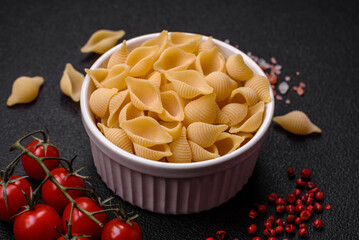 Raw Italian pasta conchiglie from durum wheat with vegetables, salt and spices