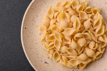 Raw Italian pasta conchiglie from durum wheat with vegetables, salt and spices