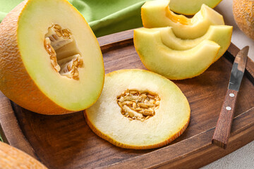 Wooden board with pieces of sweet melon on white background