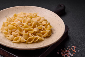 Raw Italian pasta conchiglie from durum wheat with vegetables, salt and spices