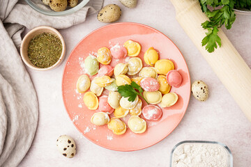 Plate with colorful raw dumplings and parsley on white background