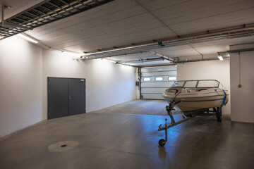 White motorboat on transport cradle in underground garage on parking lot. Sweden.