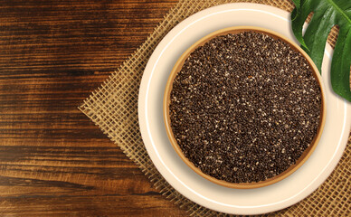 chia seeds in a bowl with wooden background and a burlap sack cloth.