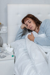 Vertical photo, mid adult Caucasian woman, sick in bed. Concept people, health.