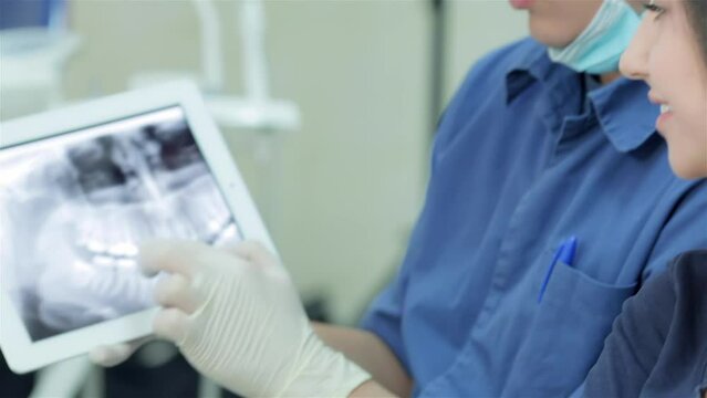 Dentist shows a close-up of an x-ray picture of her teeth on the tablet