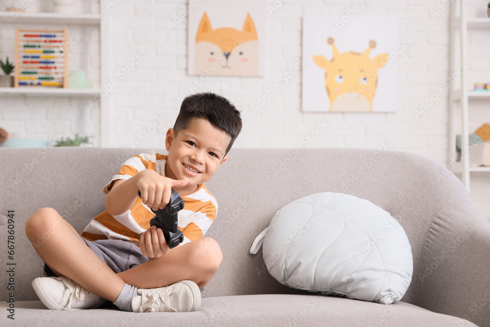 Poster little asian boy playing video game at home