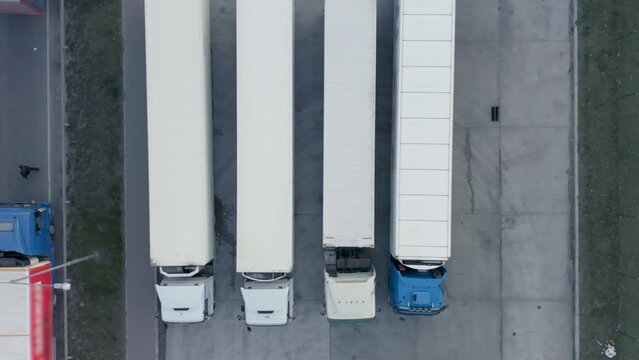 Aerial top down view of semi-trailers trucks wait at the truck stop for unload and load goods in a logistics park