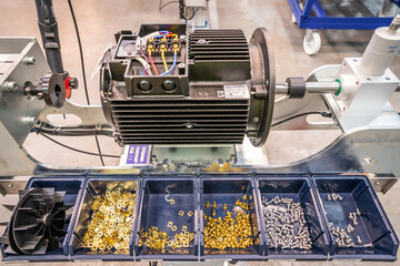 Electric motor assembly table at factory with bolts and nuts in containers